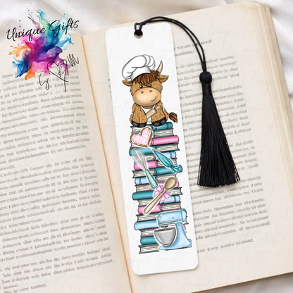 Personalised highland cow baker bookmark – cow in baker outfit on book stack – aluminium with black tassel