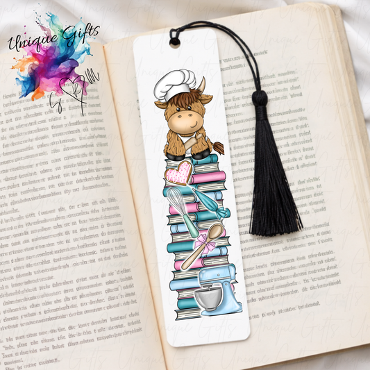 Personalised highland cow baker bookmark – cow in baker outfit on book stack – aluminium with black tassel